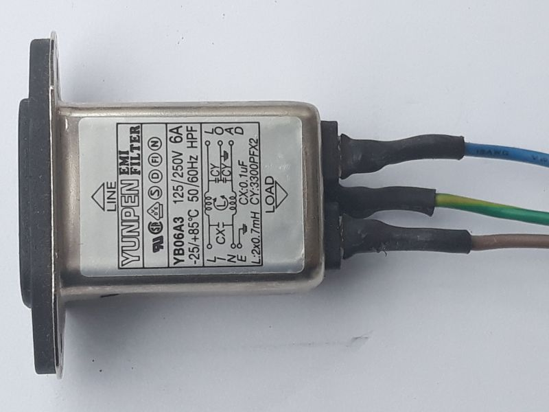 Dieser Alt-Text wurde noch nicht überprüft.

1) Kurze Zusammenfassung: Ein rechteckiges EMI‑Filter im Metallgehäuse mit Typenschild liegt auf weißem Hintergrund; rechts führen drei isolierte Adern (blau, gelb‑grün, braun) aus dem Gerät.

2) Detaillierte Beschreibung: Das silbern glänzende, rechteckige Gehäuse hat links einen schwarzen Montageflansch; auf der Oberseite befindet sich ein Etikett mit der Aufschrift „YUNPEN EMI FILTER“, Modell „YB06A3“, Nennwerten „6A“, „125/250V“, „50/60Hz“, Temperaturbereich „−25 bis +85°C“ sowie mehreren Prüf- und Zulassungszeichen. Ein Pfeil mit „LINE“ zeigt zum Flansch, ein Pfeil mit „LOAD“ nach rechts. Auf dem Etikett ist ein Schaltbild mit Bauteilangaben zu sehen, darunter „Lx: 2×0.7mH“, „Cx: 0.1µF“, „Cy: 2×3300pF X2“, mit Anschlusskennzeichnungen L, N und Erde-Symbol. Rechts treten drei Adern aus dem Gehäuse aus, jeweils mit schwarzem Schrumpfschlauch am Austritt; die Adern sind von oben nach unten blau, gelb‑grün und braun und verlaufen leicht nach rechts. Das Metall zeigt kleine Kratzer und matte Stellen; der Hintergrund ist eine glatte, weiße Fläche.