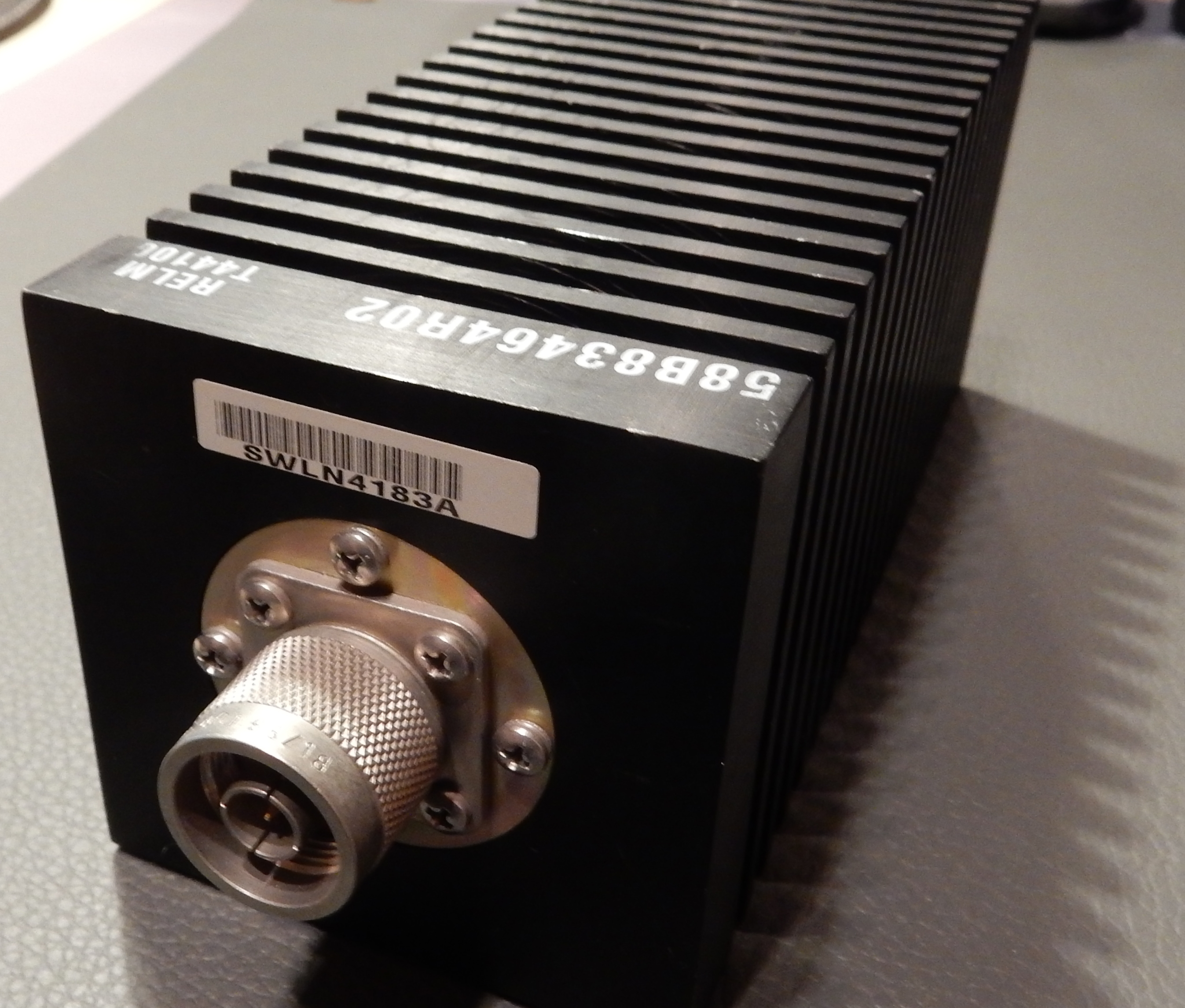 1) Kurzbeschreibung: Dummy Load mit geripptem Kühlgehäuse und großem Koaxial-N-Einbaustecker an der Stirnseite.

2) Ausführliche Beschreibung: Das Foto zeigt eine quaderförmige Dummy Load mit einem quer gerippten Kühlgehäuse und einem großen Koaxial-N-Einbaustecker an der Stirnseite.