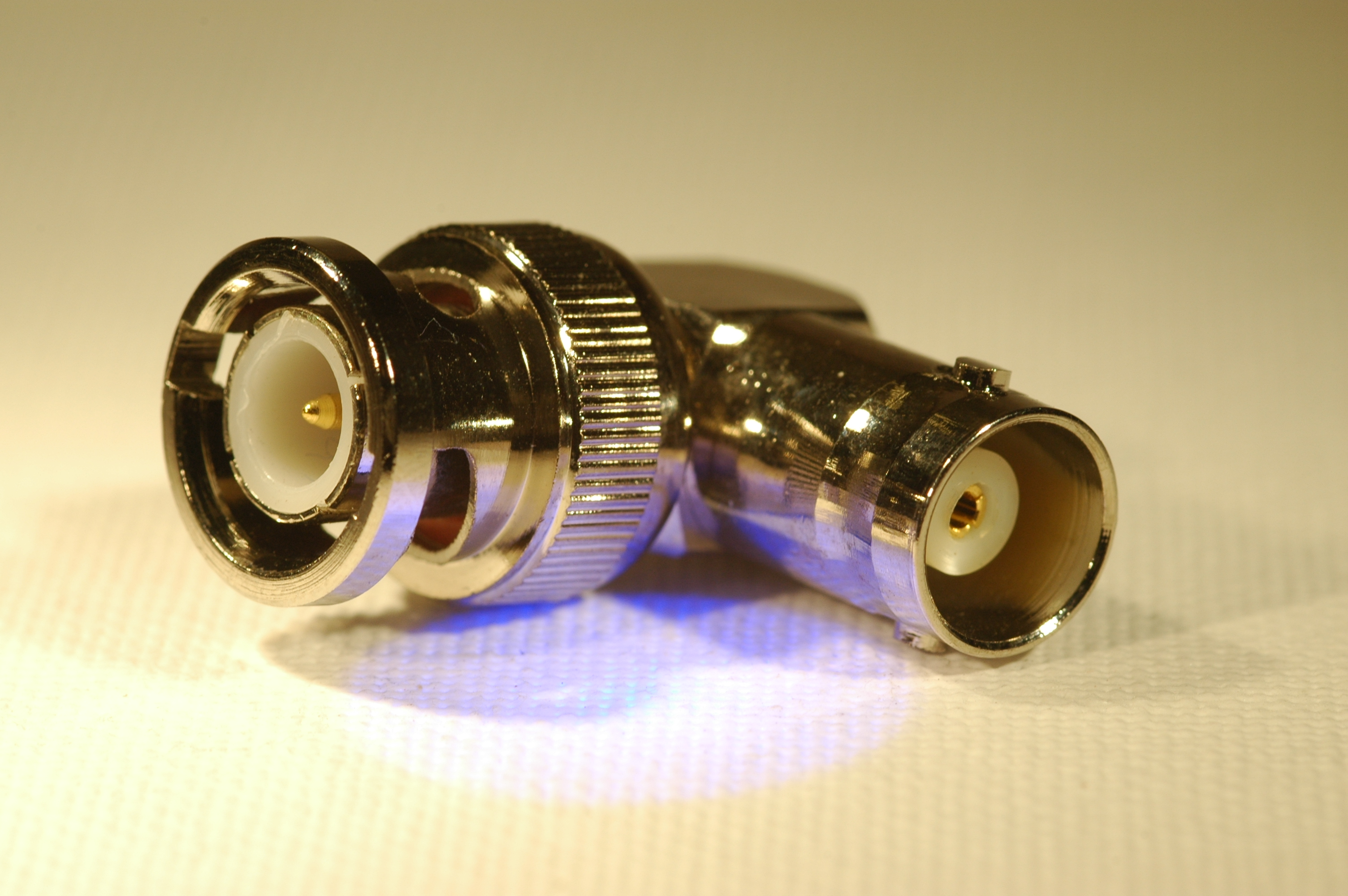 1) Kurzbeschreibung: Rechtwinkliger BNC-Winkeladapter mit Stecker links und Kupplung rechts.

2) Ausführliche Beschreibung: Das Foto zeigt einen rechtwinkligen BNC-Winkeladapter mit Stecker links und Kupplung rechts.