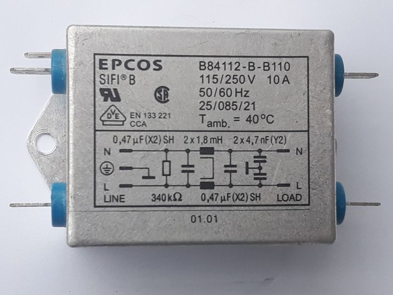 Dieser Alt-Text wurde noch nicht überprüft.

1) Kurze Zusammenfassung:
Rechteckiges, silbernes EPCOS-Bauteil im Metallgehäuse mit aufgedruckten technischen Daten und Schaltbild; an beiden Seiten ragen je zwei Anschlüsse durch blaue Isolatoren heraus.

2) Detaillierte Beschreibung:
Das Foto zeigt frontal ein graues/silbernes Metallgehäuse mit abgerundeten Kanten und einer seitlichen Befestigungslasche mit rundem Loch links. Links und rechts sind jeweils zwei flache Anschlussfahnen zu sehen, die durch blaue Isolatoren geführt werden. Auf der Gehäusefront steht oben links „EPCOS“ und „SIFI B“. Oben rechts sind Typ- und Leistungsdaten aufgedruckt: „B84112-B-B110“, „115/250V 10A“, „50/60 Hz“, „25/085/21“, „T amb. = 40°C“. Darunter befinden sich mehrere Prüf- und Normzeichen (u. a. ein „UR“-Symbol, ein rundes „CSA“-ähnliches Zeichen und ein Dreieck mit „VDE“), sowie der Text „EN 133 221 CCA“. In einem eingerahmten Feld ist ein Schaltbild mit Beschriftungen dargestellt: links „LINE“ mit „N“ und „L“, rechts „LOAD“ mit „N“ und „L“; eingezeichnet sind Kondensatoren und Drosseln, beschriftet u. a. mit „0,47 µF (X2) SH“, „2 x 1,8 mH“, „2 x 4,7 nF (Y2)“ und ein Widerstand „340 kΩ“. Links neben dem Schaltbild ist das Erdungssymbol abgebildet. Unten mittig steht „01.01“. Die Oberfläche wirkt matt und leicht gebürstet; Hintergrund ist neutral hell.
