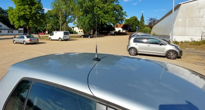 1) Kurzbeschreibung: Kurze Stabantenne mit Magnetfuß auf einem Autodach.

2) Ausführliche Beschreibung: Das Foto zeigt eine kurze Stabantenne mit Magnetfuß und Anschlusskabel, montiert in der Mitte eines Autodaches.