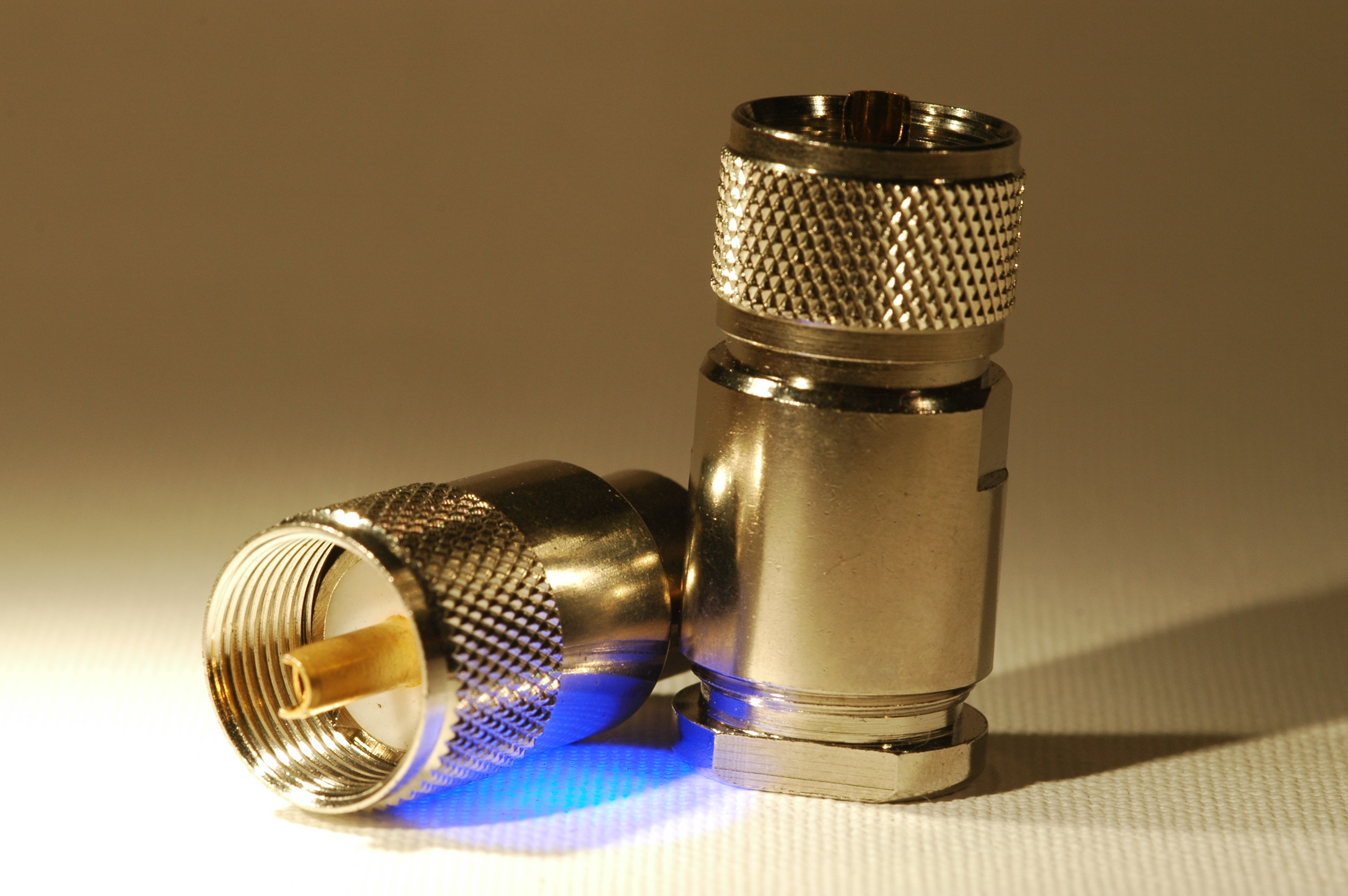 1) Kurzbeschreibung: Zwei koaxiale PL-Stecker, rechts mit und links ohne Reduzierhülse.

2) Ausführliche Beschreibung: Das Foto zeigt zwei koaxiale PL-Stecker mit Überwurfmutter mit Innengewinde und zentralem Stift. Der rechte PL-Stecker hat zudem eine Reduzierhülse, mit der auch Kabel mit geringerem Durchmesser verwendet werden können.