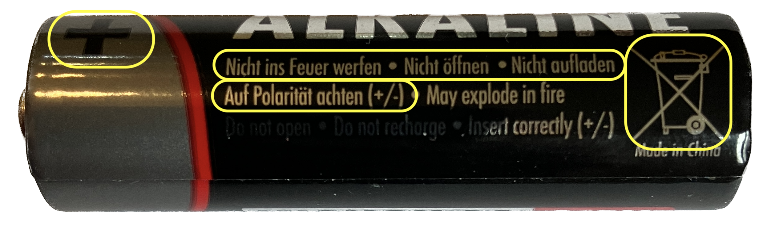 1) Kurzbeschreibung: Zylindrische Alkaline-Batterie mit gelben Markierungen für den Pluspol und mit Sicherheitshinweisen.

2) Ausführliche Beschreibung: Das Foto zeigt eine Batterie mit der Beschriftung „ALKALINE“. Auf dem Foto gibt es gelb umrandete Markierungen für den Pluspol (links), für Sicherheitshinweise „Nicht ins Feuer werfen • Nicht öffnen • Nicht aufladen“ sowie darunter „Auf Polarität achten (+/–)“ (in der Mitte) und eine durchgestrichene Mülltonne. Außerdem gibt es Sicherheitshinweise in englischer Sprache, die auf dem Foto nicht umrandet sind.
